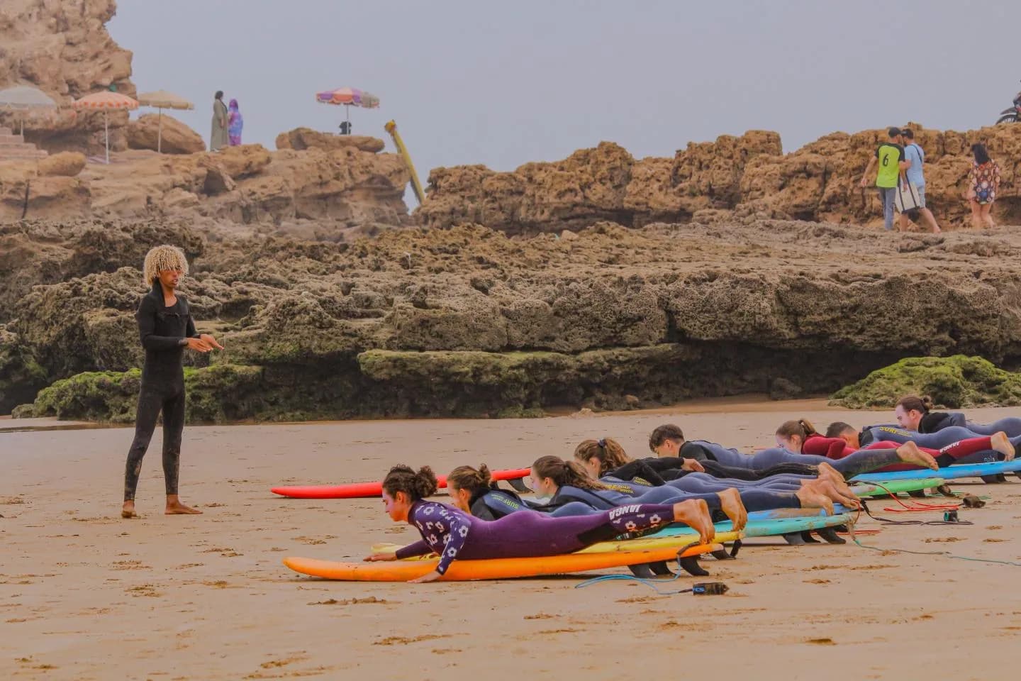 Surf instructor briefing students lying on their boards on the beach
