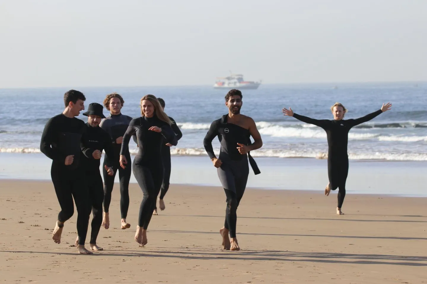 Group in wetsuits running out of the sea