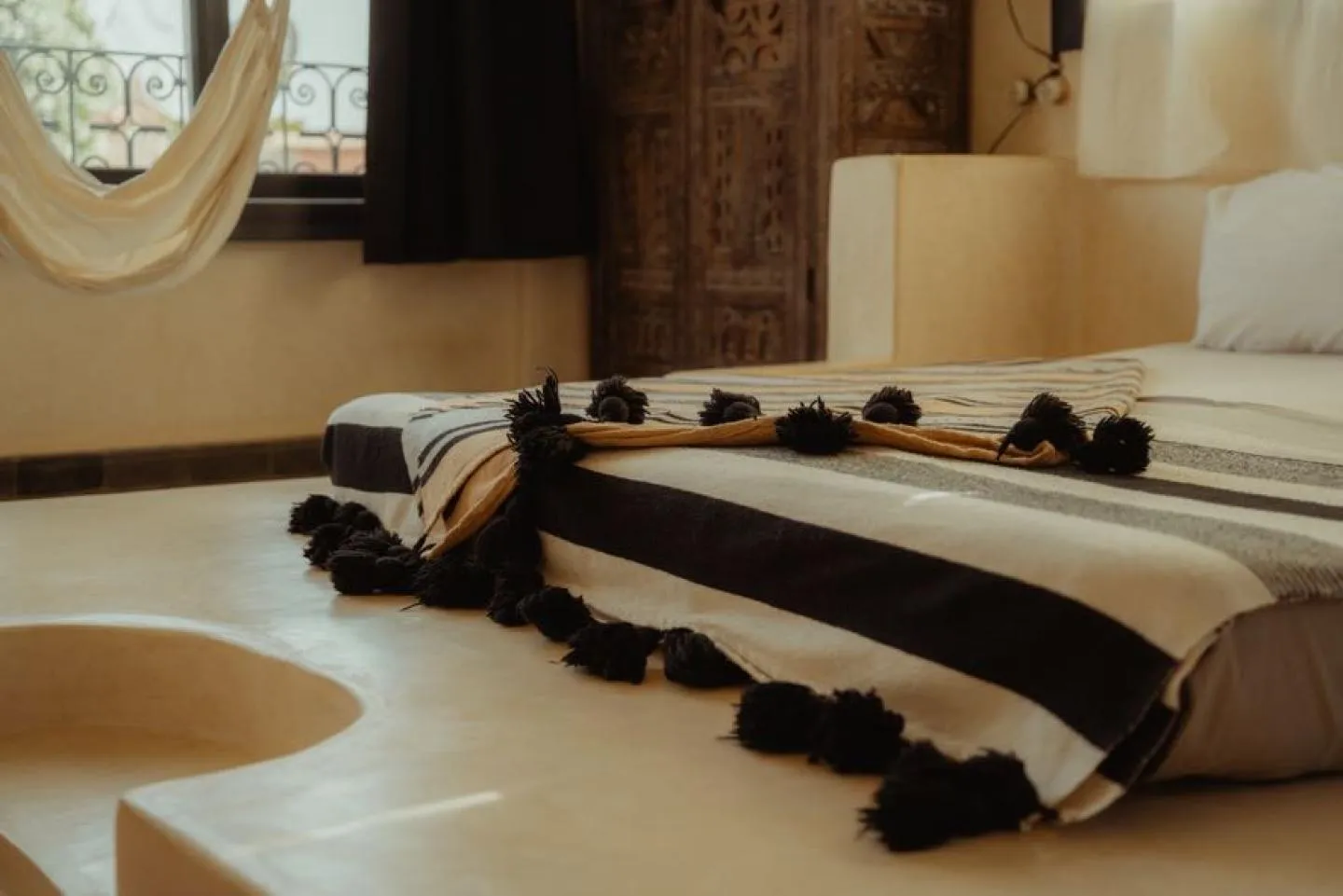 Bed with a black-and-white striped throw finished with pompom tassels