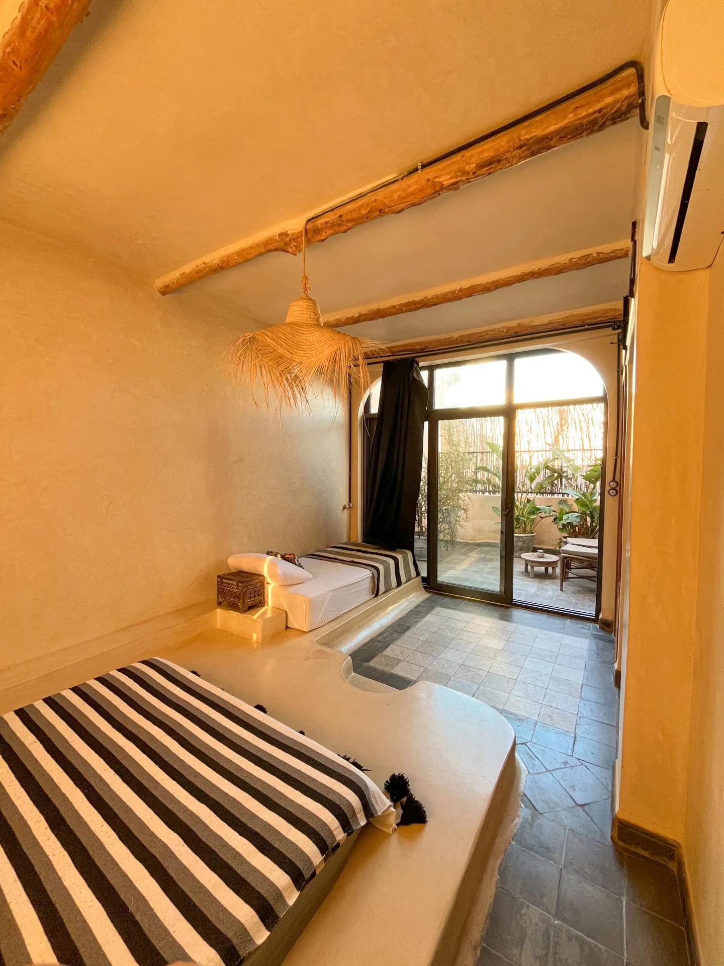 Bedroom with wooden beams, a striped bed and a door to a terrace