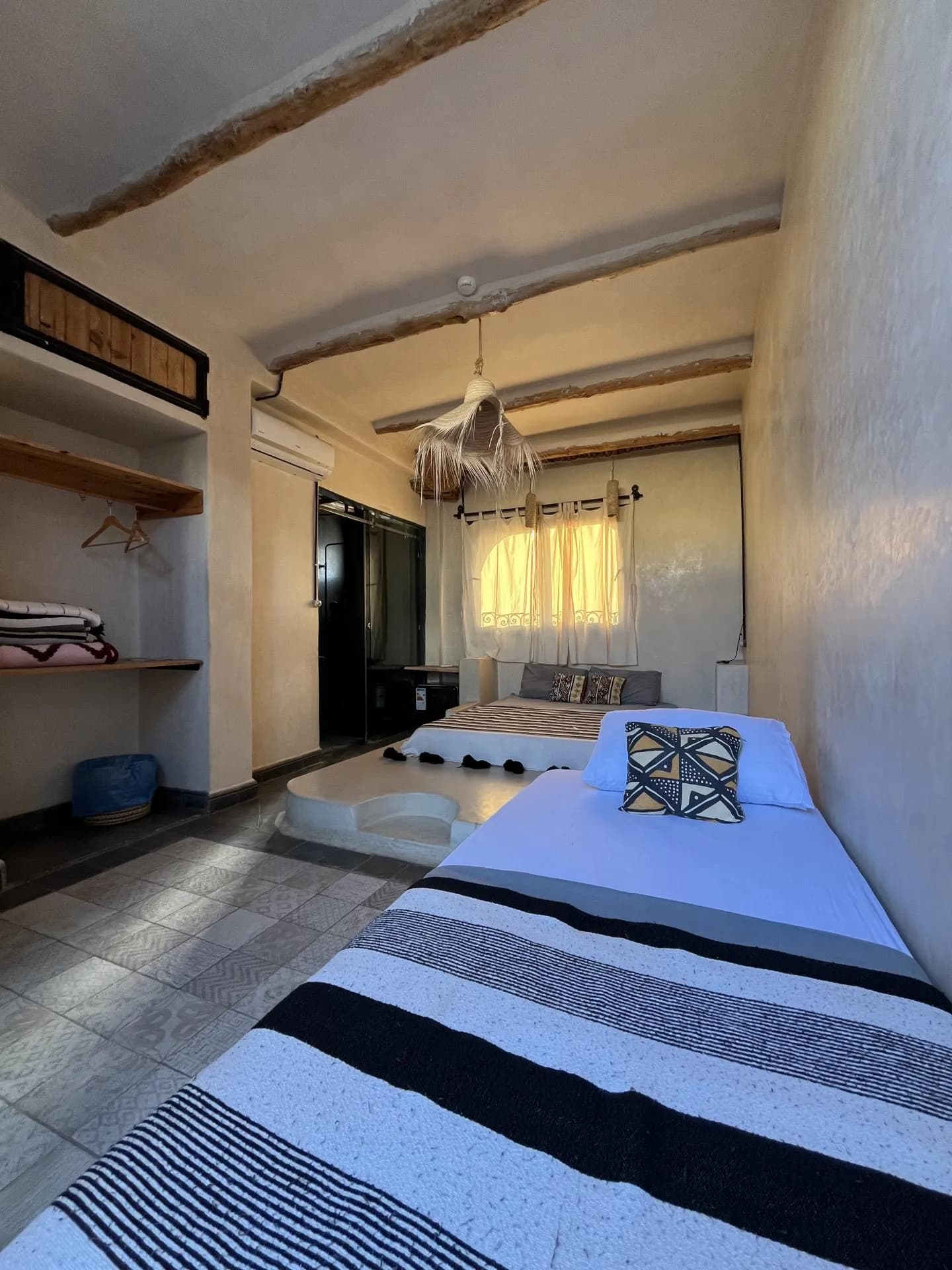 Room with a low bed, striped blanket and patterned cushion
