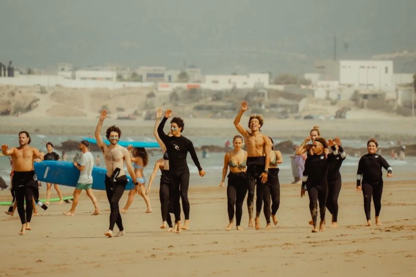 Surfers in wetsuits cheering on the beach