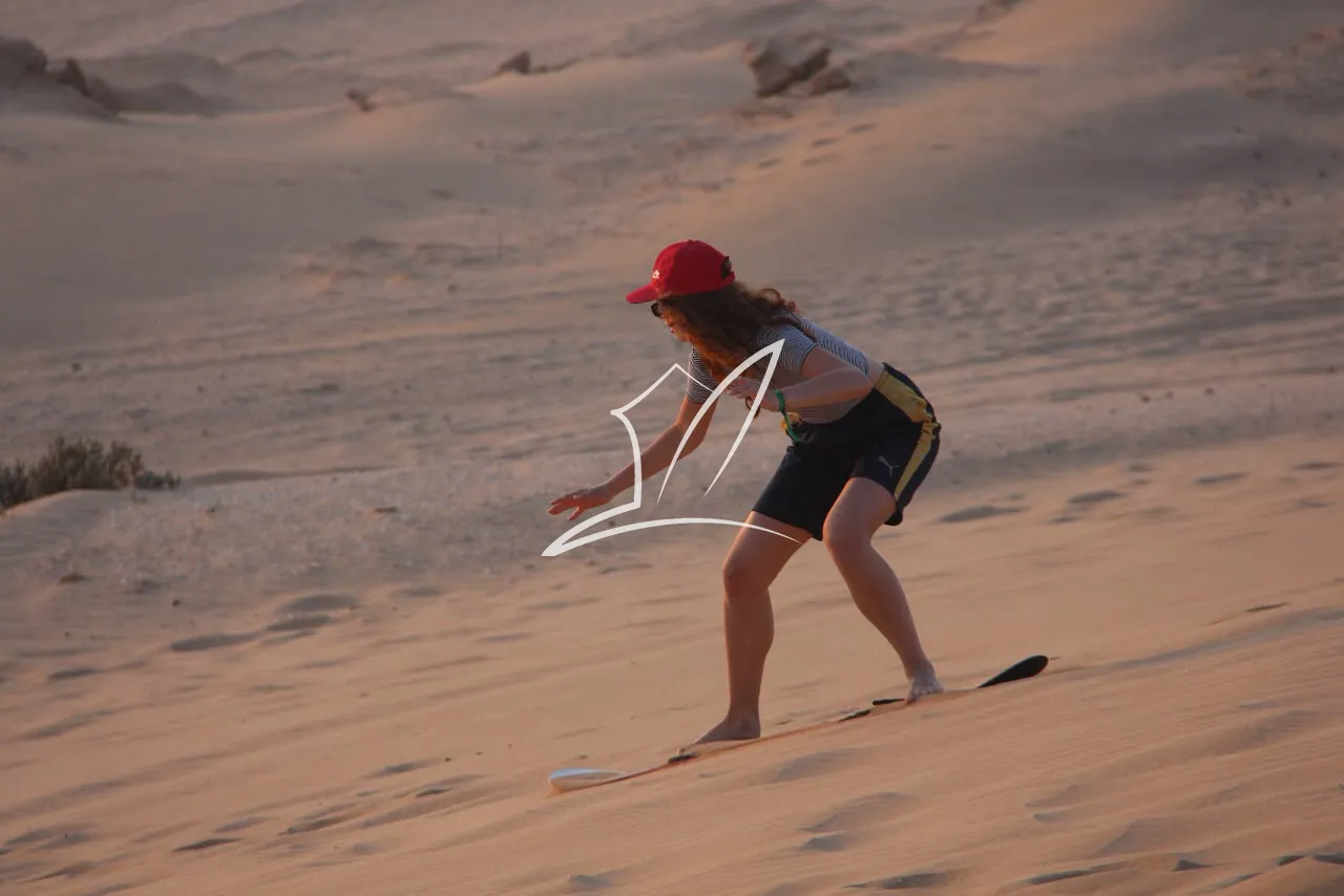 Person sandboarding down a dune