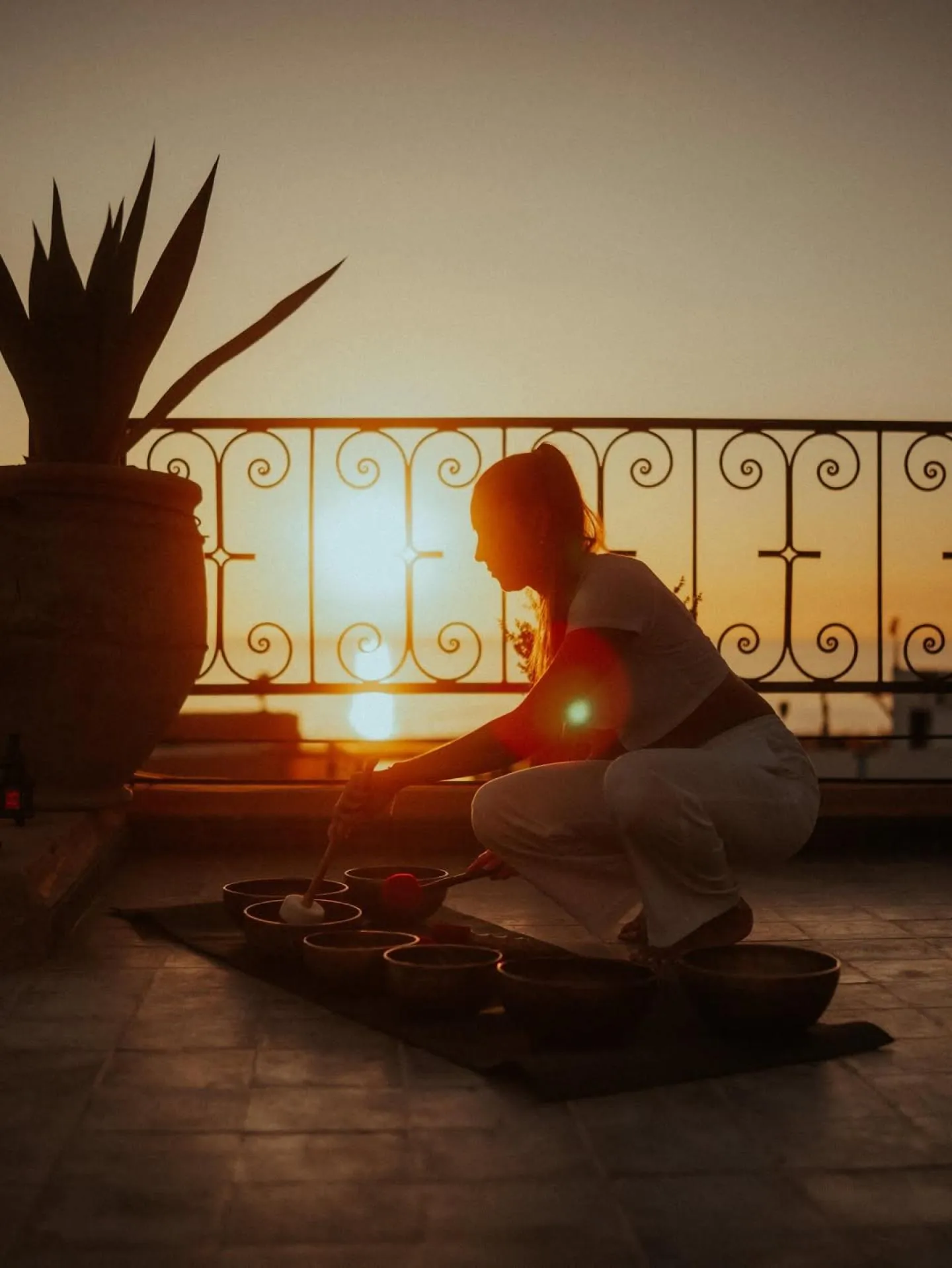 Silhouette preparing tea on a terrace at sunset