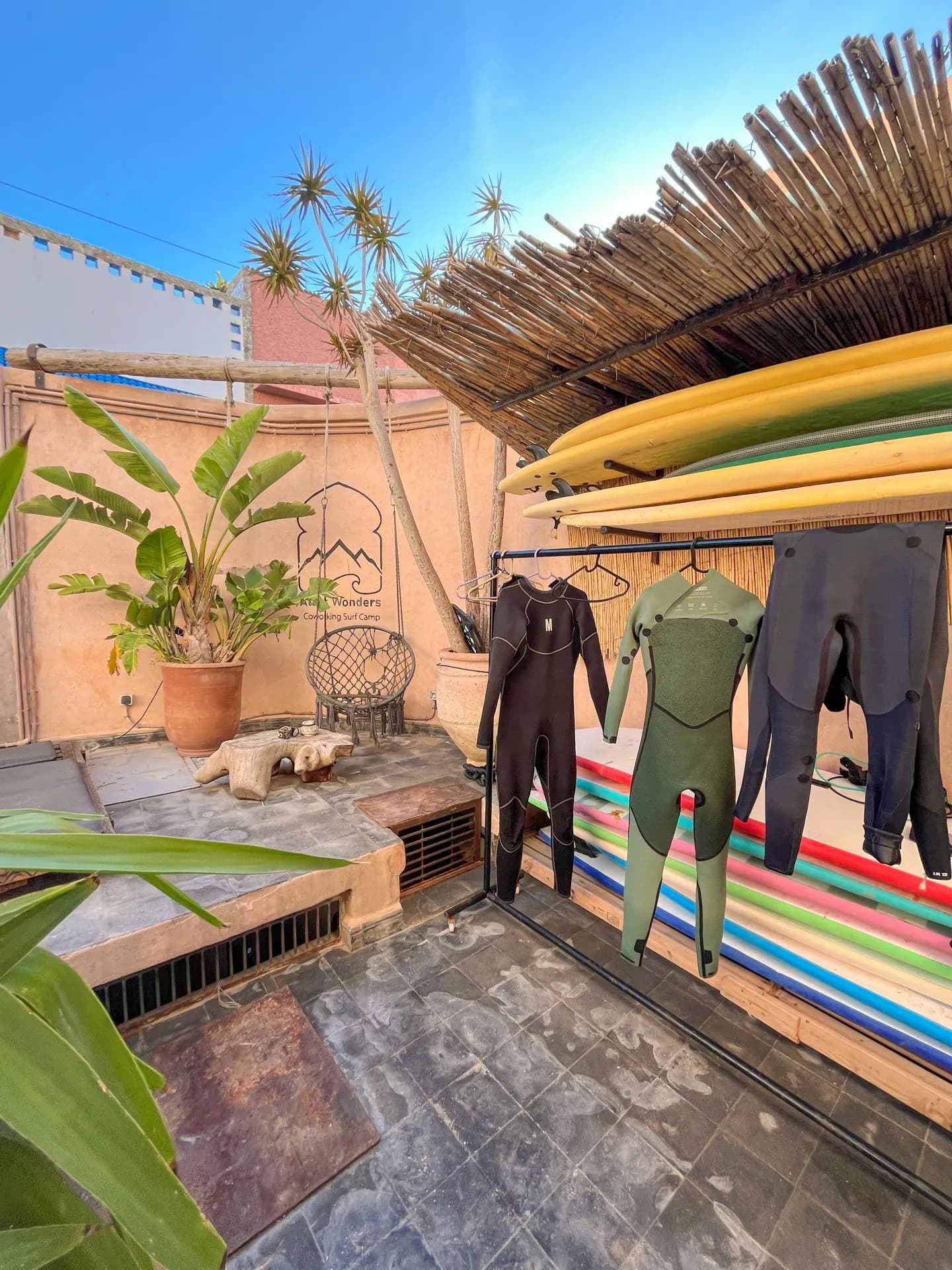 Wetsuits and surfboards drying on a terrace